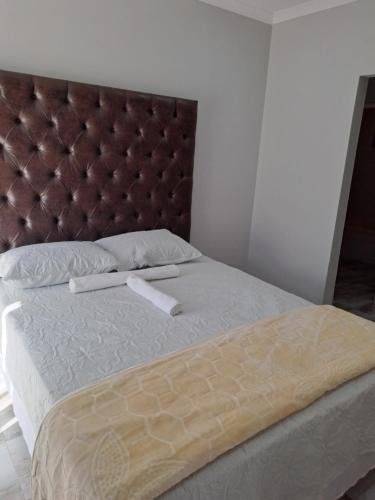 a bed with a brown headboard and two white pillows at Randhart guesthouse in Alberton