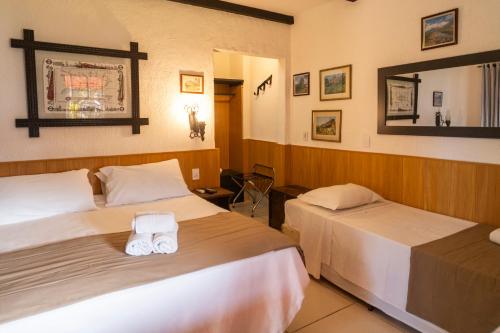 a hotel room with two beds and a mirror at Hotel Britannia in Penedo