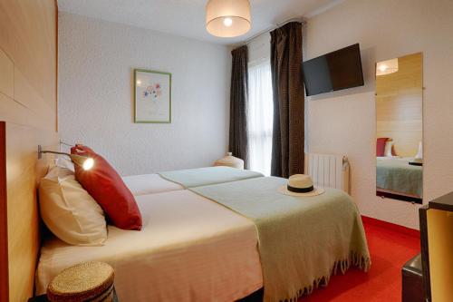 a hotel room with a bed with a hat on it at Hotel Le Branhoc - Brit Hotel Auray in Auray