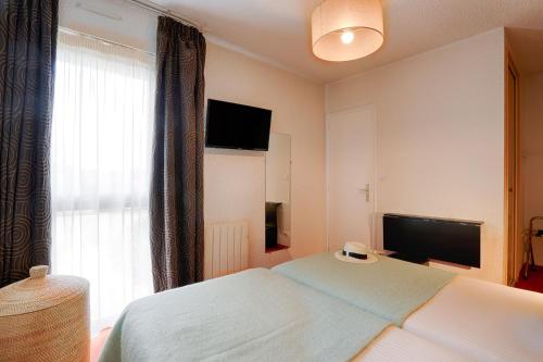 a bedroom with a bed and a flat screen tv at Hotel Le Branhoc - Brit Hotel Auray in Auray