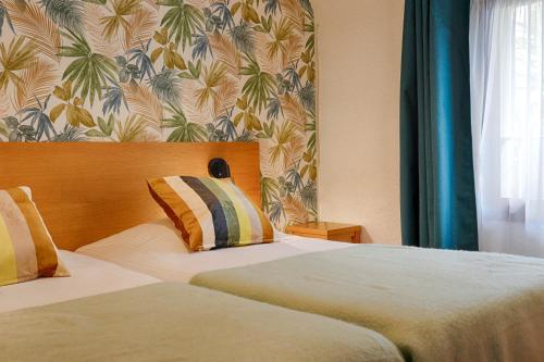 a hotel room with two beds and a wall at Hotel Le Branhoc - Brit Hotel Auray in Auray