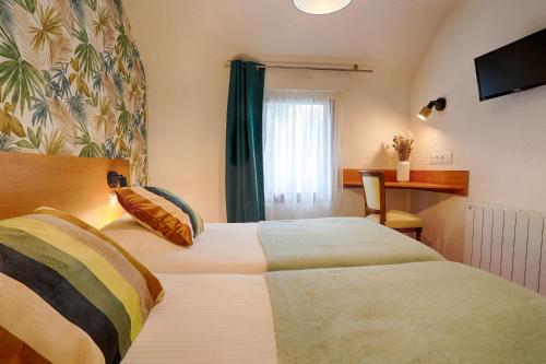 a hotel room with two beds and a window at Hotel Le Branhoc - Brit Hotel Auray in Auray
