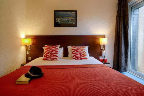a bedroom with a bed with a hat on it at Hotel Le Branhoc - Brit Hotel Auray in Auray