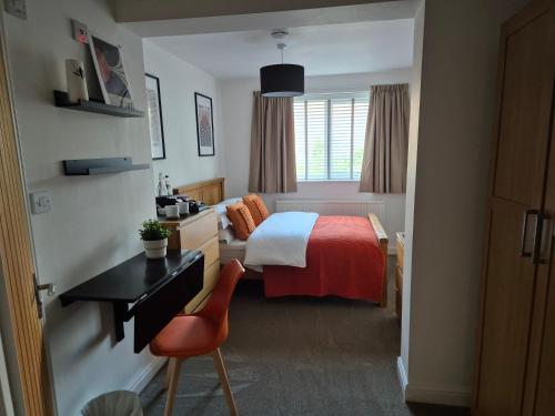 a hotel room with a bed with a desk and a chair at Carolines rooms in Cherry Hinton