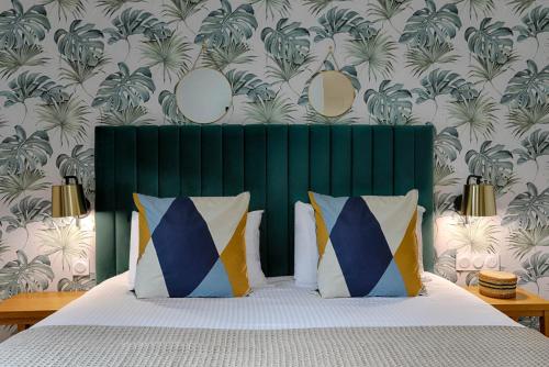 a bedroom with a bed with a green headboard and wallpaper at Hotel Le Branhoc - Brit Hotel Auray in Auray