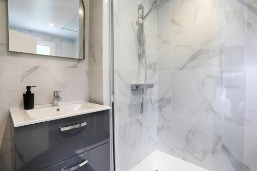 a white bathroom with a sink and a shower at Hotel Le Branhoc - Brit Hotel Auray in Auray