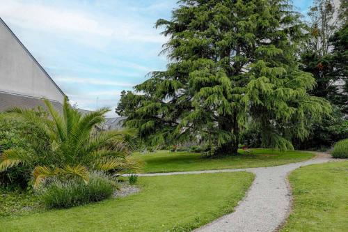 a gravel path in a garden with a tree at Hotel Le Branhoc - Brit Hotel Auray in Auray