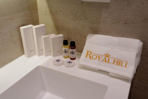 a bathroom with a white sink with a towel and two bottles at Royal Hill Hotel in Tirana
