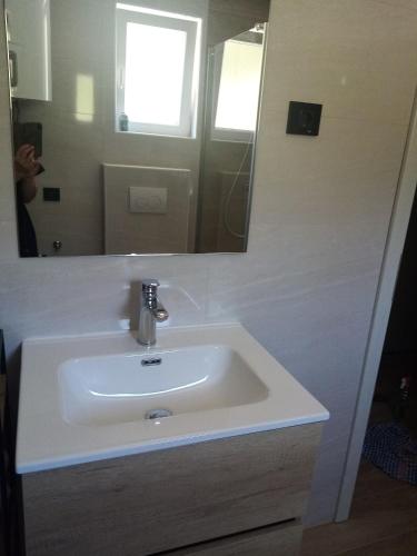 a white sink in a bathroom with a mirror at Natalija apartmani in Sveti Juraj