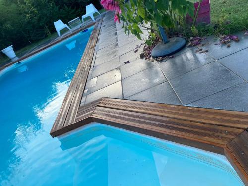 - une piscine avec un banc en bois à côté dans l'établissement Blue fish, à Gragnague