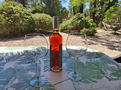 une bouteille de vin et deux verres à vin sur une table dans l'établissement Chalet les Cigalines au calme, à Fabrezan