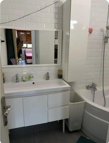 une salle de bain avec un lavabo, une baignoire et un miroir dans l'établissement Canapé lit 