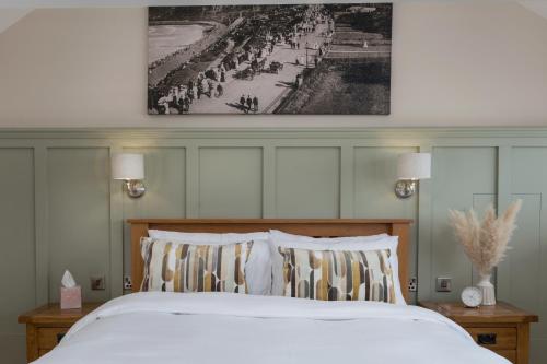 a bed with two pillows and a picture on the wall at Lighthouse Cottage Unique Apartments in Scarborough