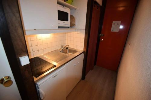 une petite cuisine avec un évier et un micro-ondes dans l'établissement Résidence Le France - Studio 2 pers- LE FRANCE - PLAGNE CENTRE MAE-5994, à Aime La Plagne