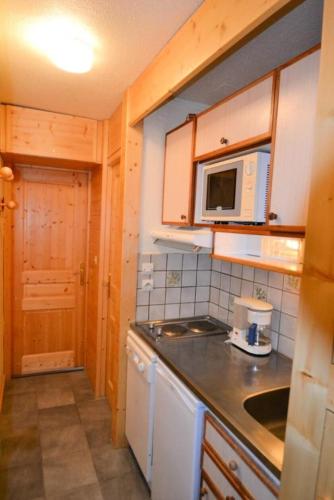 une petite cuisine avec une cuisinière et un micro-ondes dans l'établissement Résidence Le France - Studio 2 pers - LE FRANCE - PLAGNE CENTRE MAE-9584, à Aime La Plagne