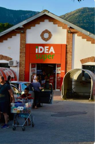 a woman with a shopping cart in front of a store at Herceg Novi Seaside Retreat with Serene Garden in Zelenika
