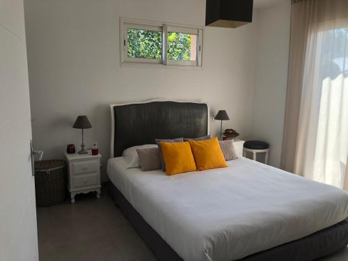 une chambre avec un grand lit avec des oreillers jaunes dans l'établissement Mini-villa mitoyenne de type F2 proche Golfe de Lava, à Appietto