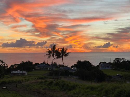 a sunset over the ocean with palm trees at Hawaii Magic Skies Farmstay in Hilo