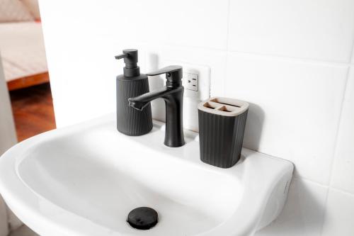 a bathroom sink with two faucets and a trash can at La Caribena Beach House- Bocas del Toro, Isla Colón, Panamá in Big Creek