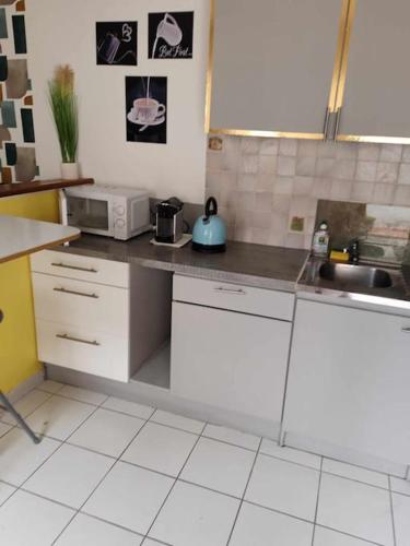 une cuisine avec des armoires blanches et un comptoir dans l'établissement or rose, à Toulouse