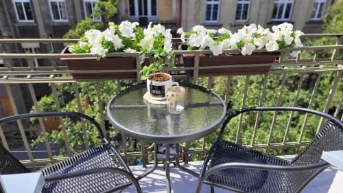 a glass table and chairs with flowers on a balcony at Klimatyczny apartament w sercu Bydgoszczy in Bydgoszcz