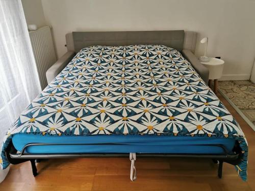 a bed in a bedroom with a blue and white quilt at RER C Les Grésillons NEAR PARIS in Asnières-sur-Seine