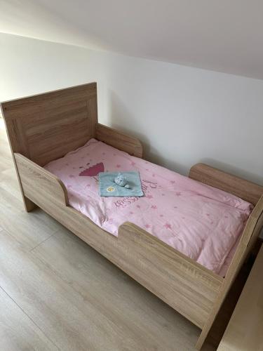 a wooden bed with a pink sheets and a book on it at Große Ferienwohnung Gästehaus NEUBAU Merzig 120m2 in Merzig