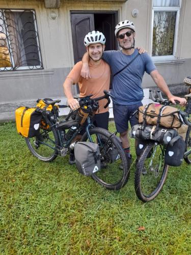 two men standing next to their bikes in the grass at Guest house Enguri in Jvari