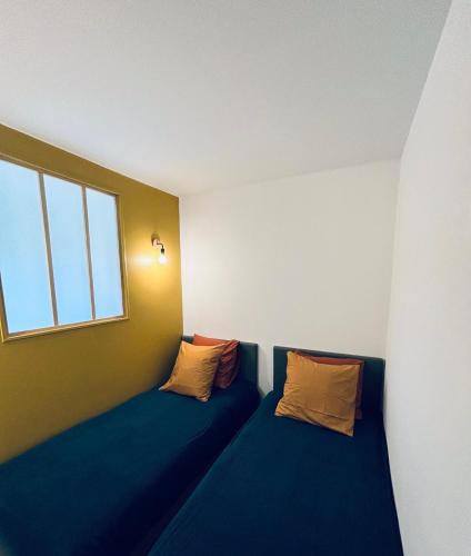 Cette chambre comprend 2 lits bleus et une fenêtre. dans l'établissement Happy Family- Appartement 3 chambres- Rez de chaussée, à Douai