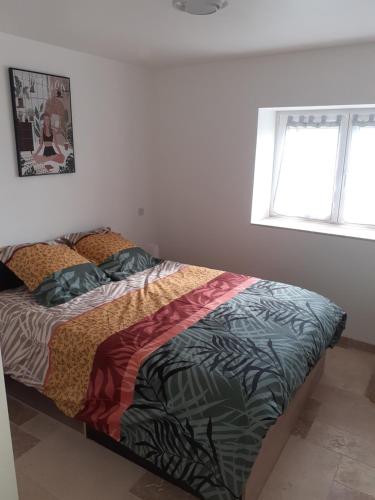 une chambre avec un lit avec une couette colorée dans l'établissement Maison Périgord, à Saint-Cernin-de-lʼHerm