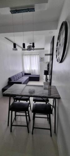 a living room with a table and two chairs and a clock at Dorothy's Door Condo in Bacolod