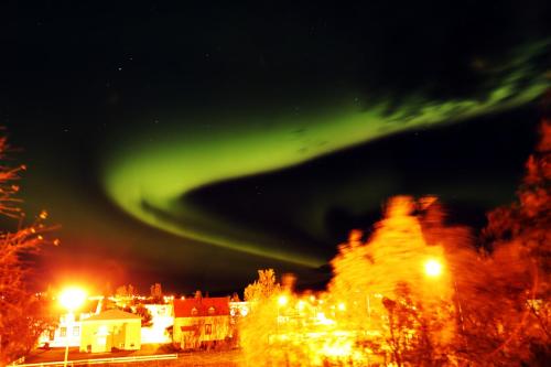 an aurora in the sky over a city at night at Private Retreat by Arctic Circle in Húsavík