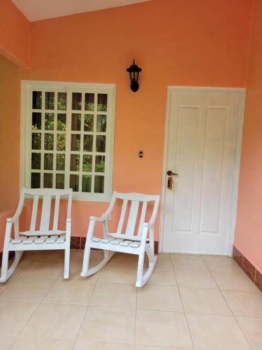 two chairs sitting on a porch with an orange wall at Hotel Museo El Ceibo in San José del Sur