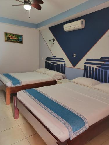 two beds in a room with a ceiling fan at Hotel Museo El Ceibo in San José del Sur