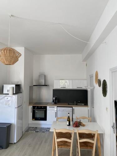 une cuisine blanche avec une table et des chaises dans l'établissement Appartement Cosy avec vue sur le château, à Chinon