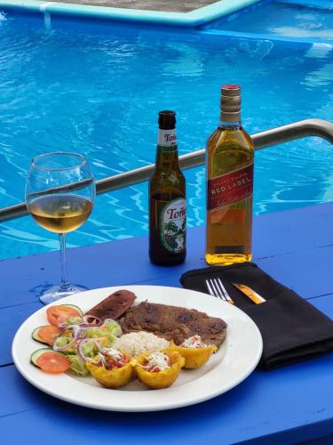 a plate of meat and vegetables and a glass of wine at Hotel Museo El Ceibo in San José del Sur