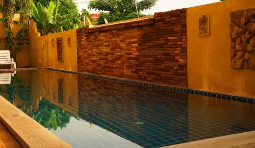 a swimming pool next to a brick wall at Hathai House in Lamai