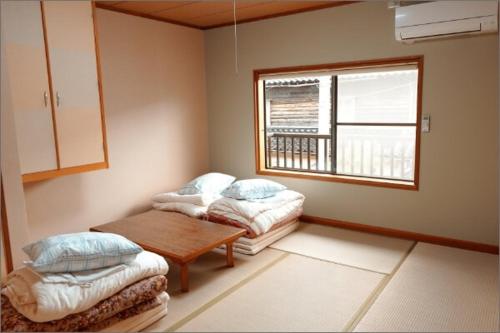 a room with two beds and a table and a window at 旧GATE80香住 無人宿 完全セルフ 予約メッセージ欄確認要す スマートロック 暗証番号チェックイン 素泊まり専門 アメニティ持参で格安滞在 セコム24h監視 駐車場10台 in Kami