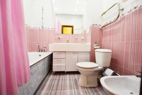 a pink bathroom with a toilet and a sink at Hotel Erofey in Khabarovsk