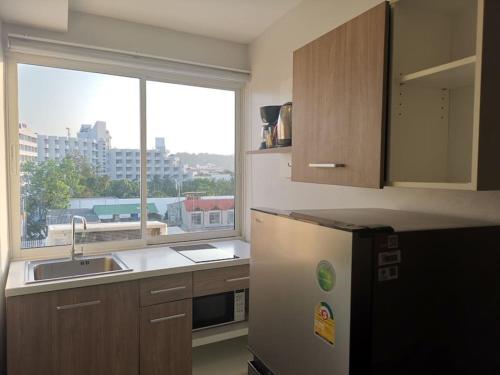 a kitchen with a sink and a refrigerator and a window at Luxury beach studio 9 floor in Pattaya