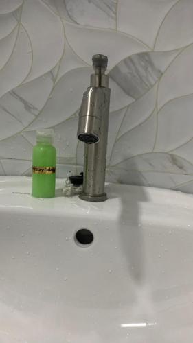a faucet and a green bottle on a sink at Bilik Ubaidillah in Gerik