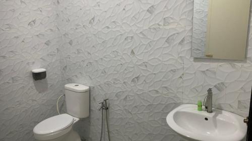 a white bathroom with a toilet and a sink at Bilik Ubaidillah in Gerik