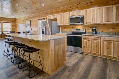 a kitchen with wooden cabinets and a large island with bar stools at NEWLY Built! 5BR-5BH-Hottub-WIFI-Theater-Pool Tble in Pigeon Forge