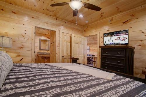 a bedroom with a bed and a flat screen tv at NEWLY Built! 5BR-5BH-Hottub-WIFI-Theater-Pool Tble in Pigeon Forge