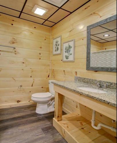 a wooden bathroom with a toilet and a mirror at NEWLY Built! 5BR-5BH-Hottub-WIFI-Theater-Pool Tble in Pigeon Forge