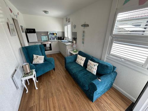a living room with two blue couches and a kitchen at 33B South Shore Village in Bridlington