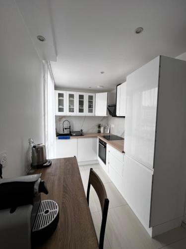 une cuisine avec des armoires blanches et une table en bois dans l'établissement Très beau t3 neuf à franconville, à Franconville