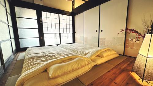 a large bed in a room with large windows at 古民家ワーケーション ふふ庵｜駅徒歩5分｜ゆる旅｜屋根在りBBQ施設｜テレワーク in Ōhara