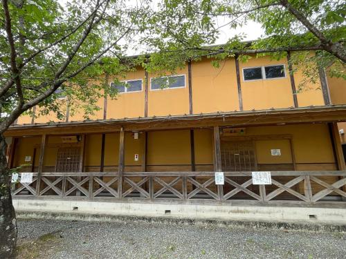 a yellow building with a tree in front of it at 源泉かけ流し離れの宿 きなっせ in Yamaga
