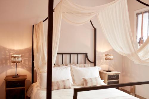 a bedroom with a canopy bed with two lamps at Diles & Rinies in Tinos Town